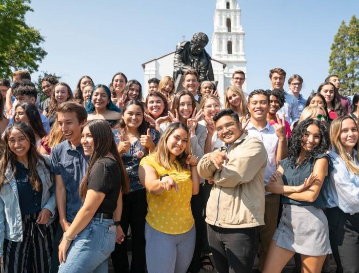 Students in a group smiling in front of the saint mary's college campus